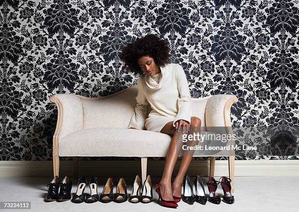 woman sitting on sofa, trying on shoes - calzature nere foto e immagini stock