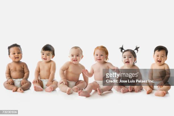 studio shot of babies sitting in row - diaper stockfoto's en -beelden