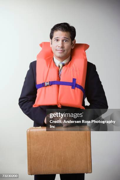 studio shot of businessman wearing life jacket and holding briefcase - life jacket stock-fotos und bilder