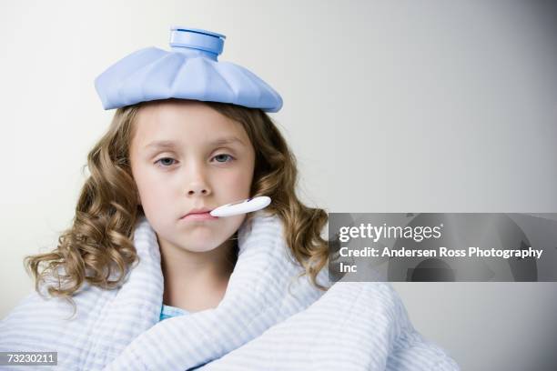 studio shot of sick young girl with thermometer in mouth - fever fotografías e imágenes de stock