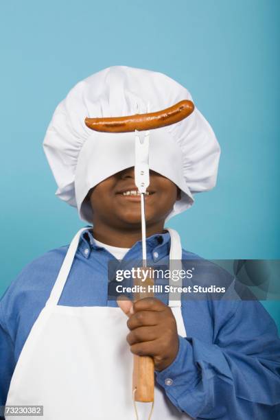 studio shot of african boy wearing chef's hat over eyes and holding hot dog - hill street studios bildbanksfoton och bilder