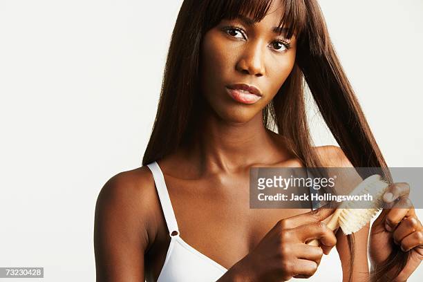 studio shot of african woman wearing bra and brushing hair - glattes haar stock-fotos und bilder