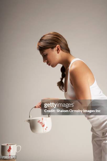 side view of woman holding teapot over teacup - holding flowers stock pictures, royalty-free photos & images