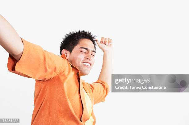 low angle studio shot of young man dancing - homme enthousiasme sourire fond blanc photos et images de collection