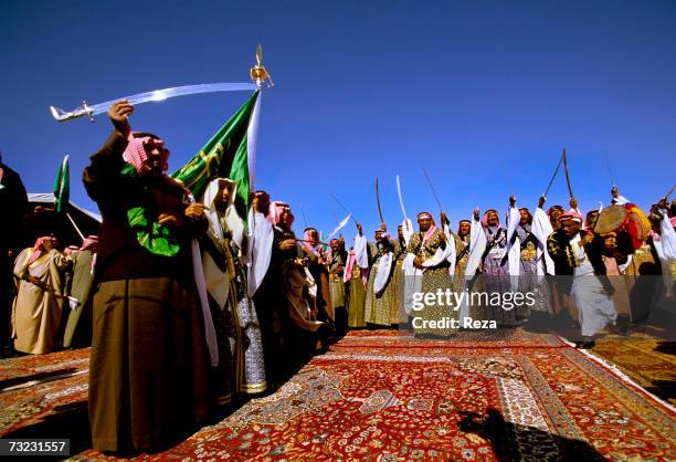 Prince Mishaal bin Abdulaziz Al Saud, wrapped in the Saudi flag, and Al Saud princes perform the traditional Bedouin war dance using swords called...