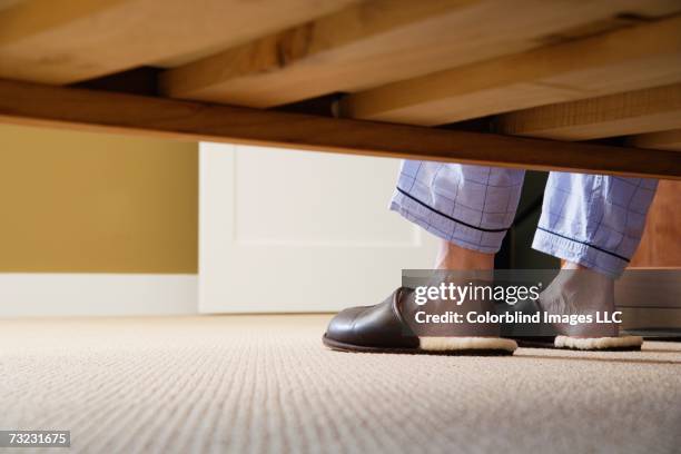 man's feet in slippers next to bed - chinelos imagens e fotografias de stock