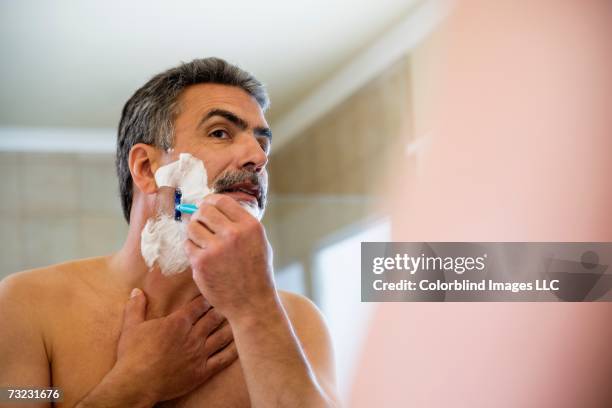 middle-aged man shaving face - scheren stockfoto's en -beelden