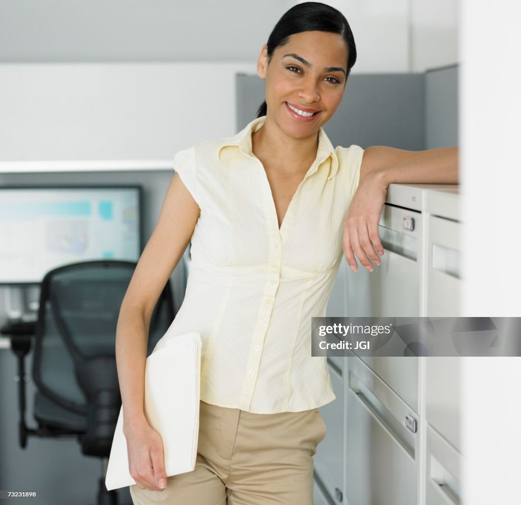 African businesswoman leaning against file cabinet