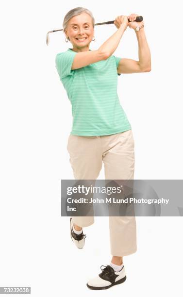 studio shot of senior woman playing golf - senior golf swing stock pictures, royalty-free photos & images