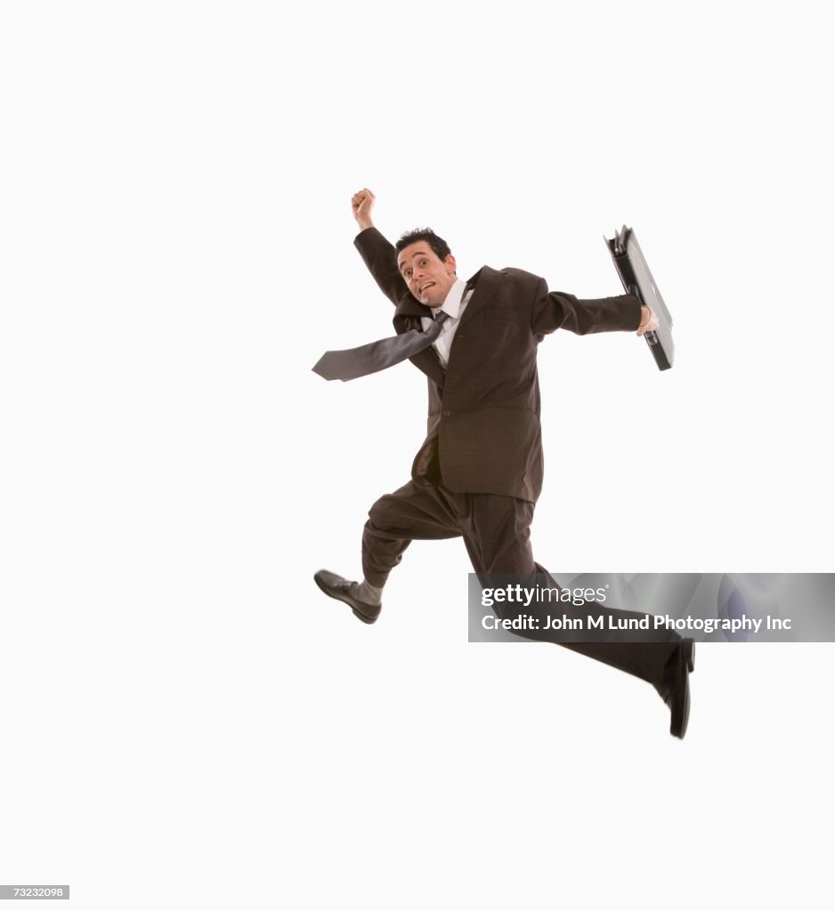 Studio shot of businessman jumping with briefcase