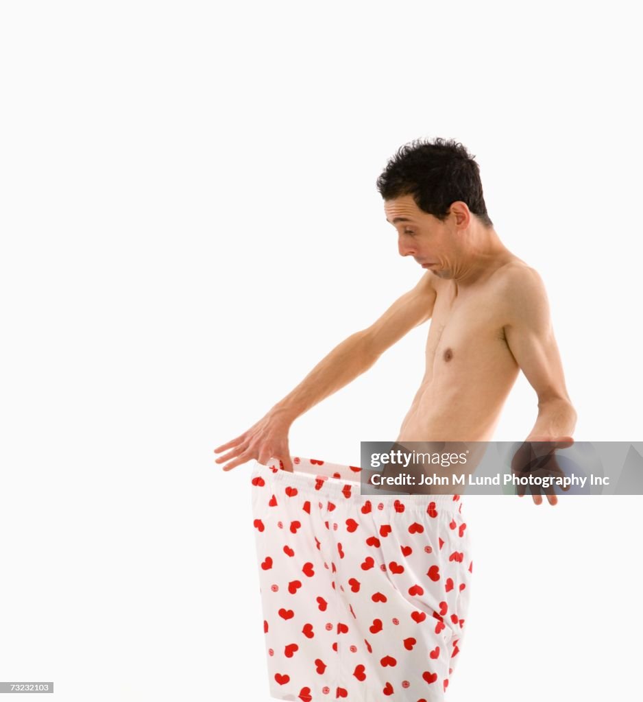 Studio shot of man pulling waist of boxer shorts out and looking down