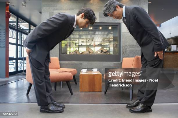 two businessmen bowing to each other in cafe - david cameron greets the prime minister of japan stockfoto's en -beelden