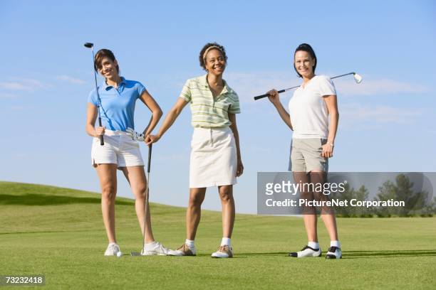 three young women with golf clubs on golf course - women golf stock pictures, royalty-free photos & images