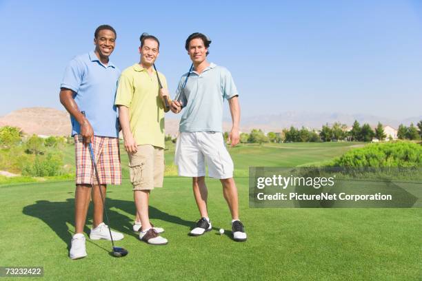 three young men with golf clubs on golf course - young men golfing stock pictures, royalty-free photos & images