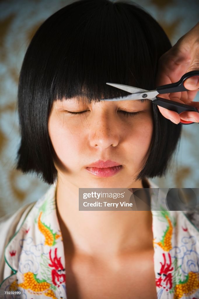 Close up of young Asian woman having bangs trimmed