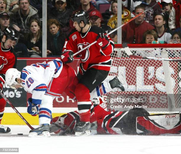 Martin Brodeur of the New Jersey Devils makes a sprawling save as his teammate Brad Lukowich clears Jason Krog of the New York Rangers out of the...