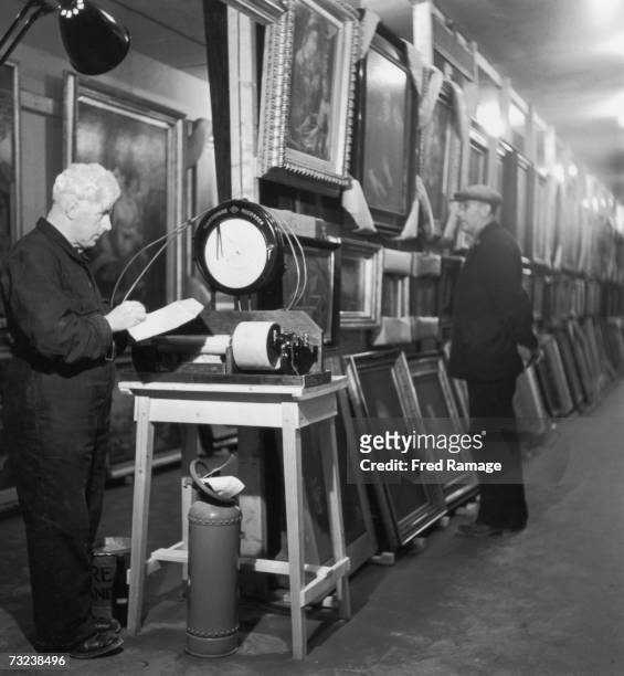 Engineer in charge J.R. Jones takes a reading of the relative humidity in a subterranean chamber at Manod Quarry, north Wales, where paintings from...