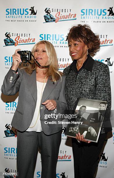 Singer Nancy Sinatra takes a picture while standing with Altovise Davis at the Sirius Satellite Radio launch of the "Siriusly Sinatra" Channel at the...