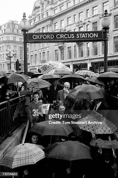 In pouring rain, city commuters crowd into Oxford Circus underground station in London's west end shopping district, May 2001.