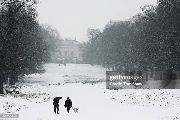 People walk their dog during snowfall over Richamond Park on February 8, 2007 in London, England.Travel chaos grips Southern England as heavy snow...