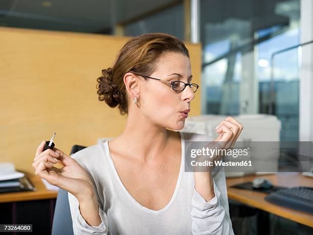 woman in office, applying nail polish, blowing, close-up - perder el tiempo fotografías e imágenes de stock