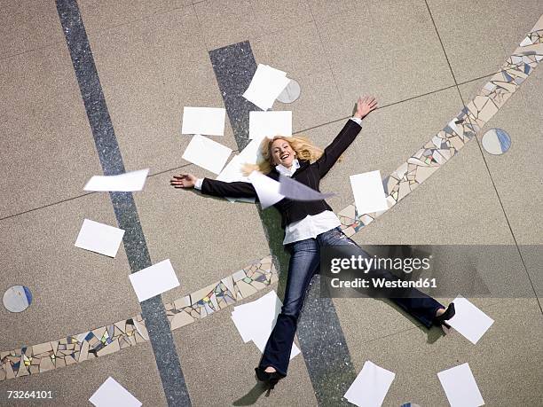 woman lying on floor surrounded by papers, elevated view - jambes écartées photos et images de collection