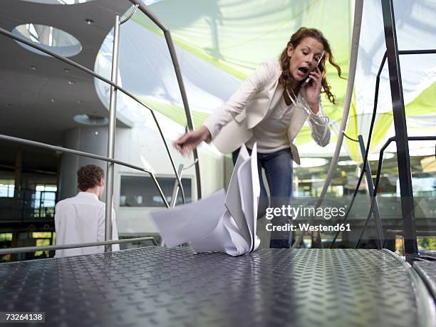 young businesswoman using mobile phone, papers falling on floor - man falling down stairs stock pictures, royalty-free photos & images