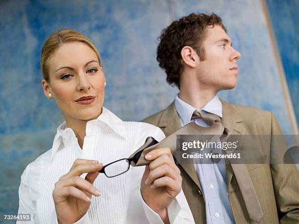 business woman cleaning spectacles with man´s tie - portrait of pensive young businessman wearing glasses stock-fotos und bilder