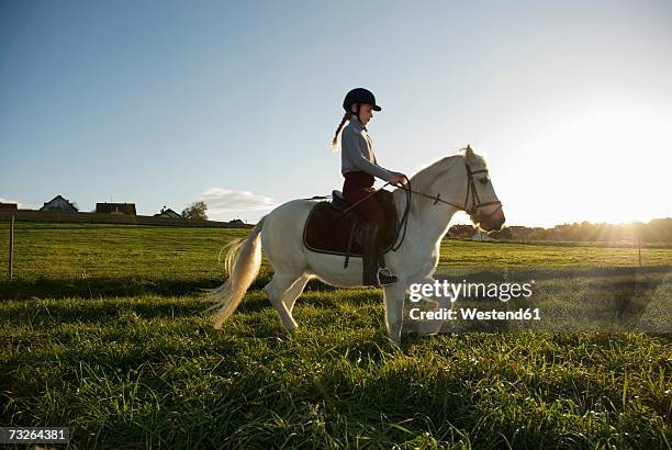 girl (7-9) riding pony, side view - animal riding stockfoto's en -beelden