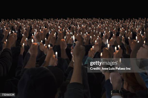 rear view of people holding lit lighters up in air - cigarette lighter stockfoto's en -beelden