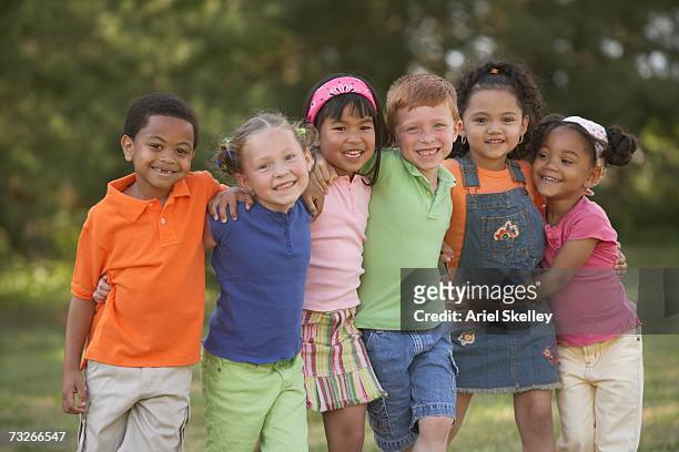 group of young children smiling and hugging outdoors - kids smiling multiple nationalities stock pictures, royalty-free photos & images