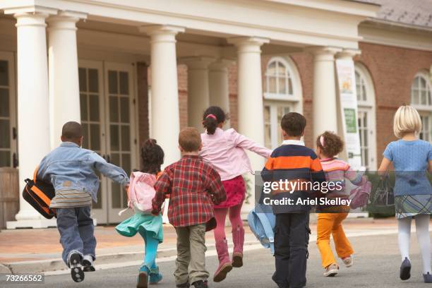 rear view of young students running to building - arriving late class stockfoto's en -beelden