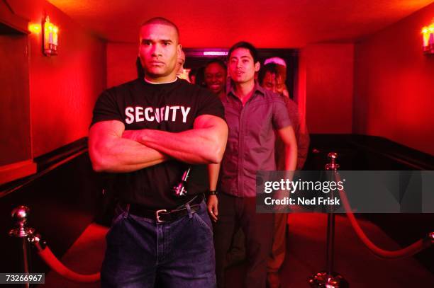 african male bouncer with arms crossed in front of line of people - ドアマン ストックフォトと画像