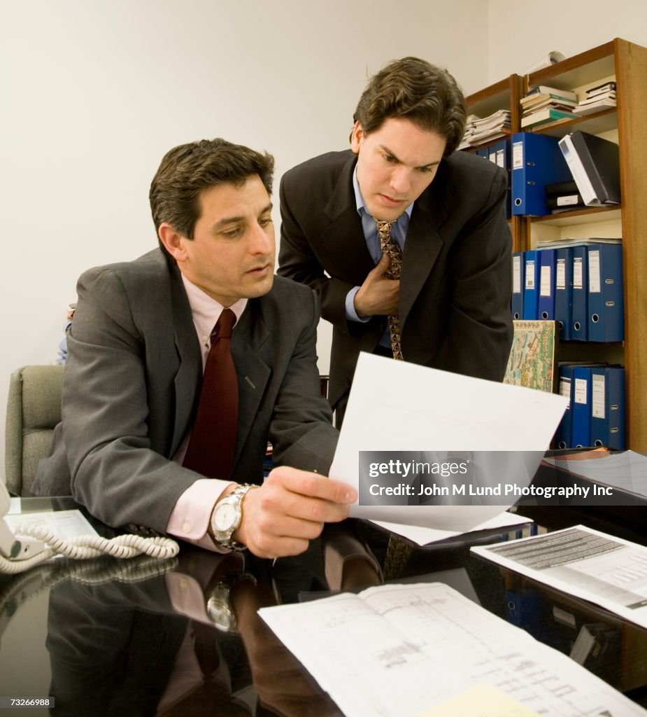 Two businessmen looking at paperwork in office
