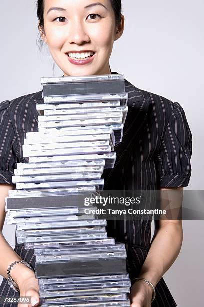 asian woman holding stack of cds and smiling - cd ストックフォトと画像