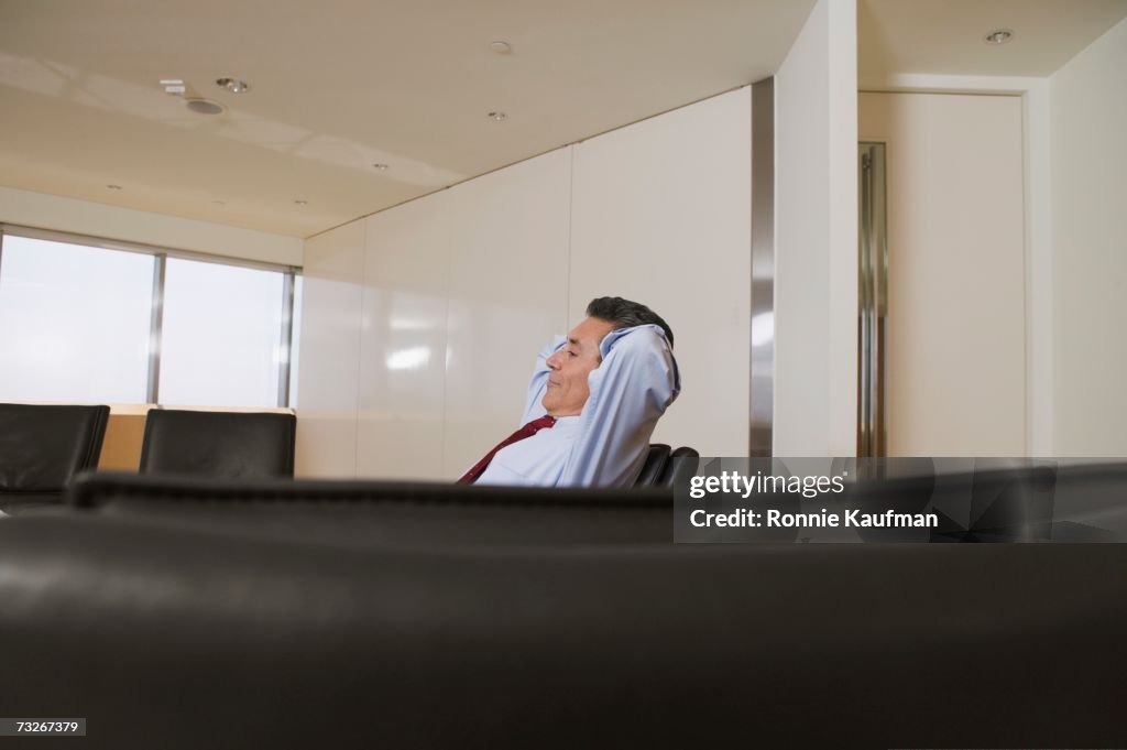 Businessman sitting with arms behind head