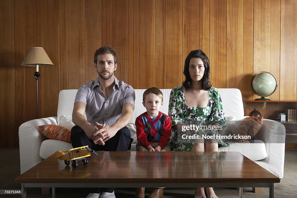 Eltern und Sohn (3-5) sitzt auf Sofa im Wohnzimmer