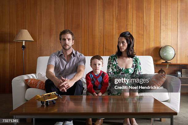 parents and son (3-5) sitting on couch in living room - envy stock pictures, royalty-free photos & images