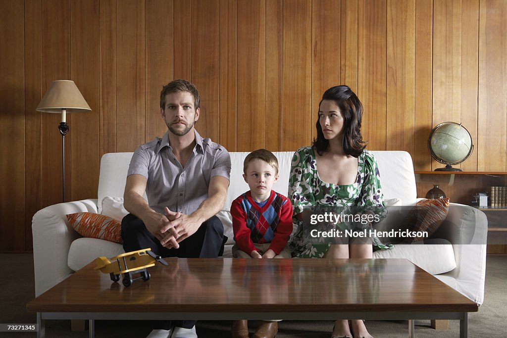 Pais e filho (3-5) sentada no sofá na sala de estar