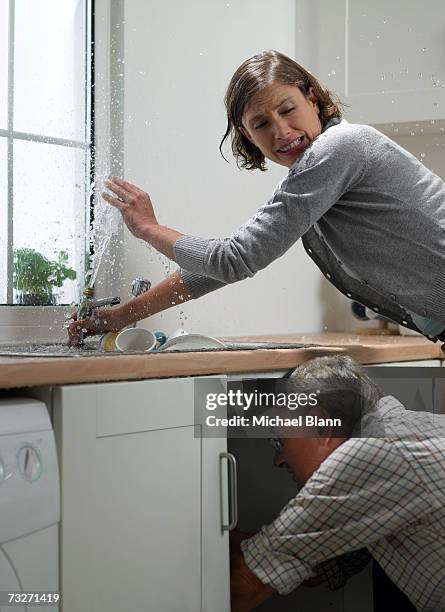 man and woman trying to fix sink in kitchen - water sprayer stock pictures, royalty-free photos & images