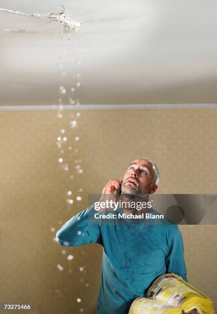 man with a leaking ceiling using phone - flooded home stock pictures, royalty-free photos & images