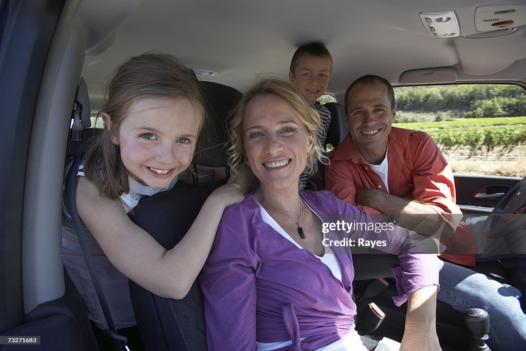 Family with daughter (7-9) and son (6-8) smiling in car