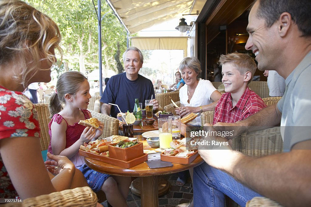 Three generation family with son (11-13) and daughter (7-9) eating at outdoor restaurant