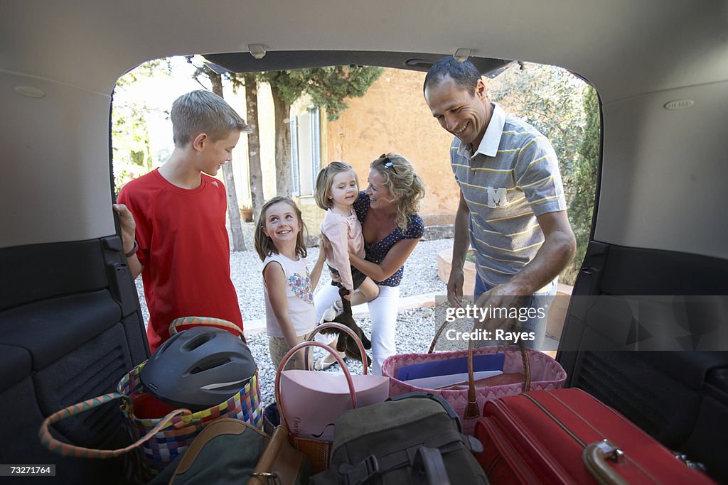 Family with son (11-13) and daughters (3-9) packing mini van