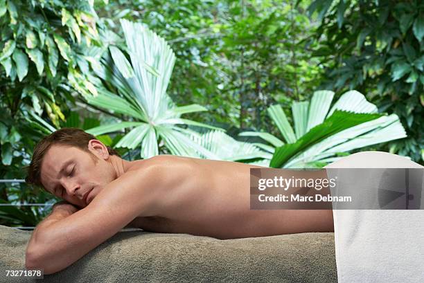 man lying on massage table at health spa - banc de massage photos et images de collection