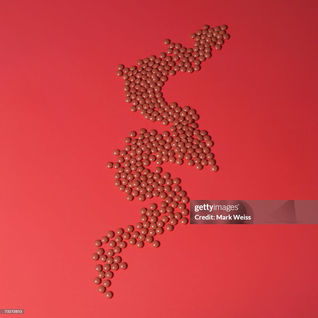 "Pills arranged on red background, elevated view, close-up"