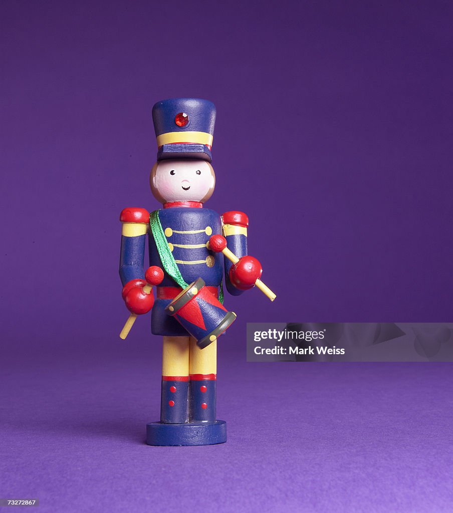 "Blue toy soldier holding drum set, close-up"