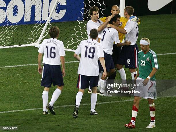 Goalkeeper Tim Howard of the USA celebrates a 2-0 win in front of the goal with teammates as Adolfo Bautista of Mexico leaves the field during an...