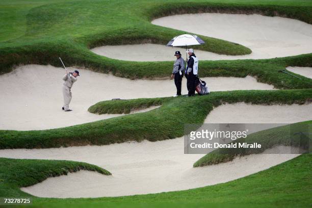 Amatuer John Scarpa hits out of the bunker on the 11th hole as Omar Uresti and caddie watch during the 2nd round of the AT&T Pebble Beach National...