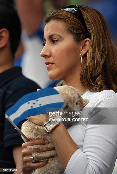 San Salvador, EL SALVADOR: Una simpatizante de la seleccion de Honduras carga su cachorro mientras observa el partido frente a Panama el 11 de...